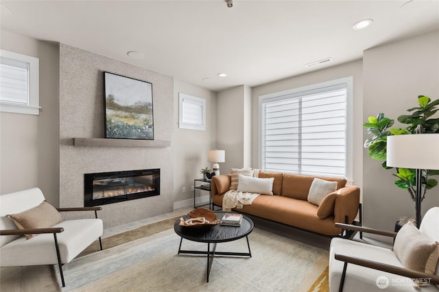 living area featuring baseboards, a fireplace, visible vents, and recessed lighting