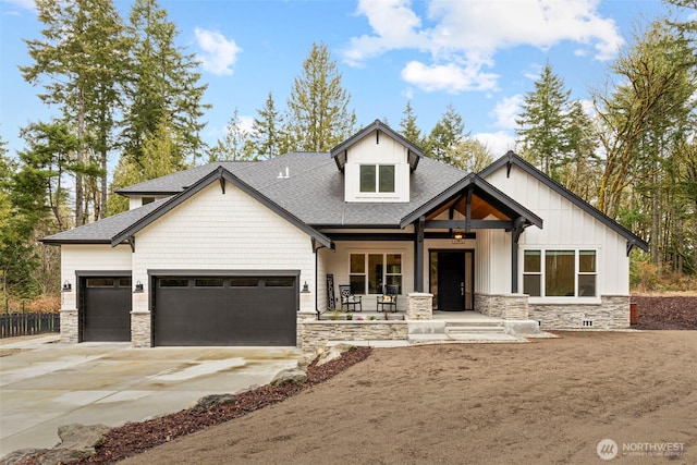 view of front of home with stone siding, a porch, an attached garage, and driveway