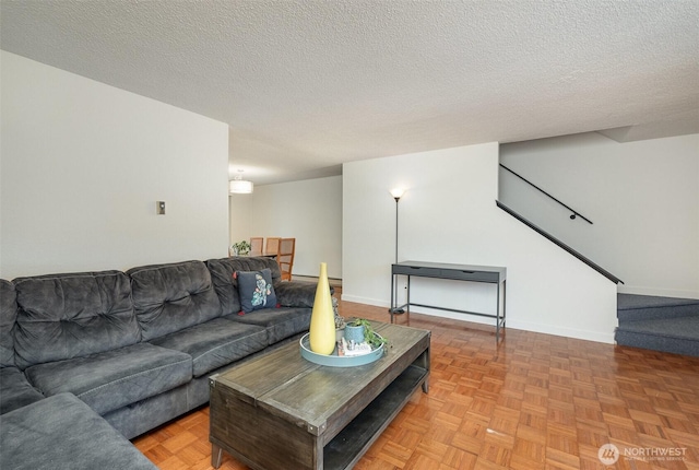 living area with stairs, baseboards, and a textured ceiling