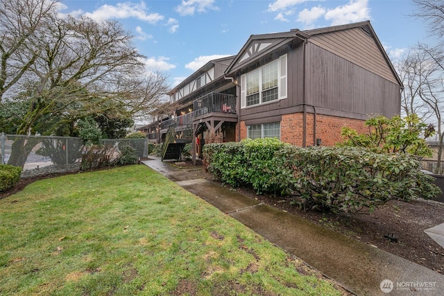 exterior space with brick siding, a yard, stairway, and fence