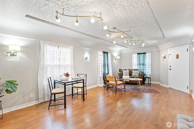 dining space featuring a textured ceiling, baseboards, and wood finished floors