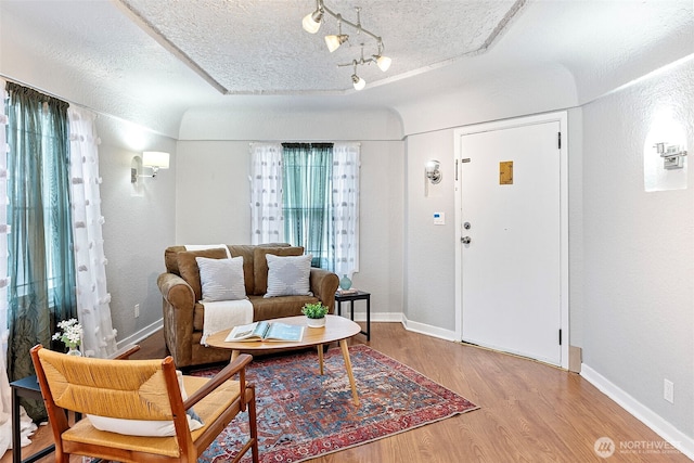 interior space featuring a textured ceiling, wood finished floors, and baseboards