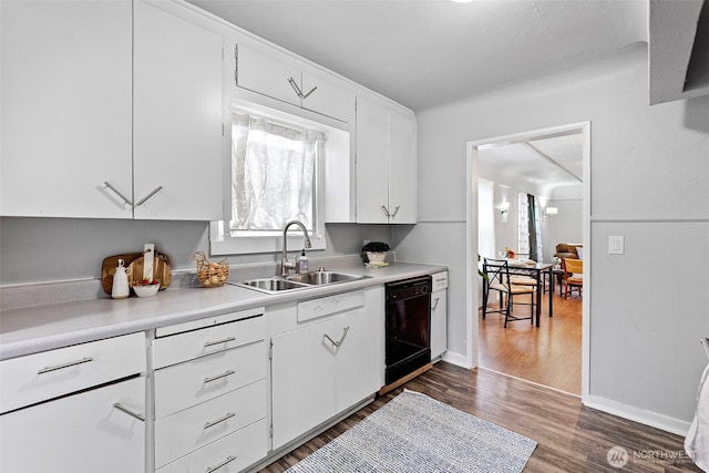 kitchen with black dishwasher, light countertops, a sink, and white cabinetry