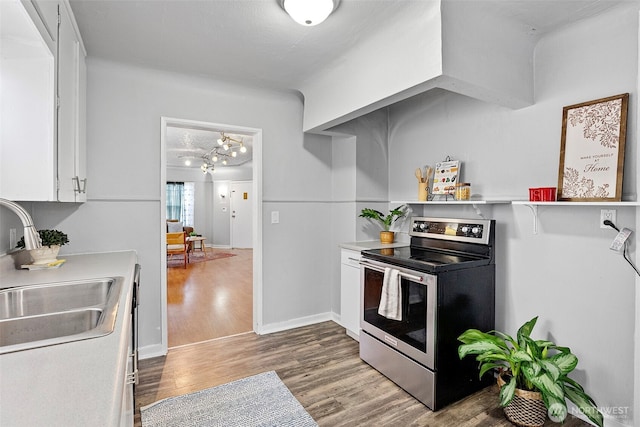 kitchen featuring stainless steel electric range oven, light countertops, white cabinets, a sink, and wood finished floors