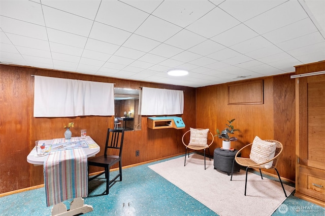 sitting room with baseboards, light floors, and wooden walls