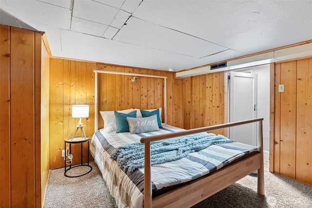 bedroom with carpet, visible vents, and wooden walls