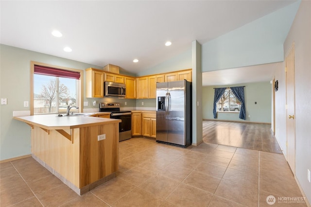 kitchen with light tile patterned floors, light countertops, appliances with stainless steel finishes, vaulted ceiling, and a peninsula