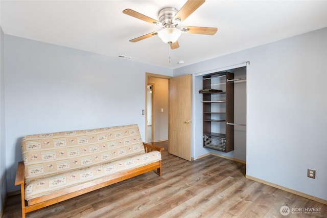 unfurnished room featuring baseboards, wood finished floors, visible vents, and a ceiling fan