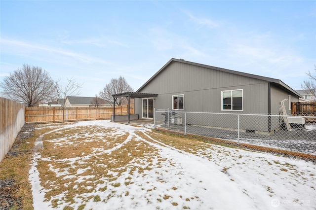 snow covered property featuring a fenced backyard and a pergola