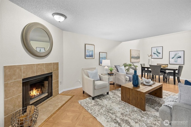 living room featuring a textured ceiling, a tile fireplace, and baseboards