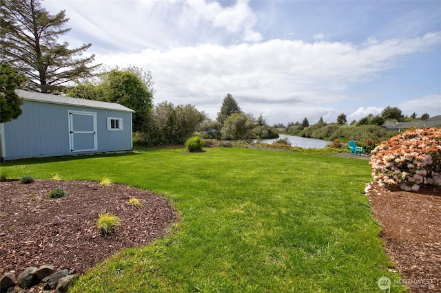 view of yard featuring a water view, a storage unit, and an outbuilding