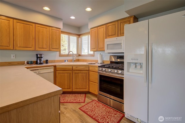 kitchen with recessed lighting, white appliances, a sink, light countertops, and light wood finished floors