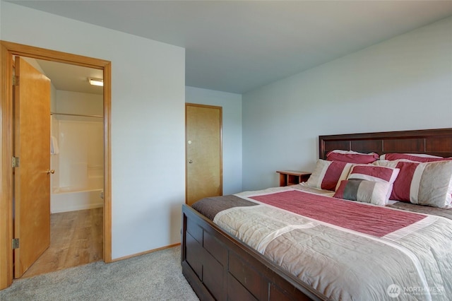 bedroom with light colored carpet, connected bathroom, and baseboards