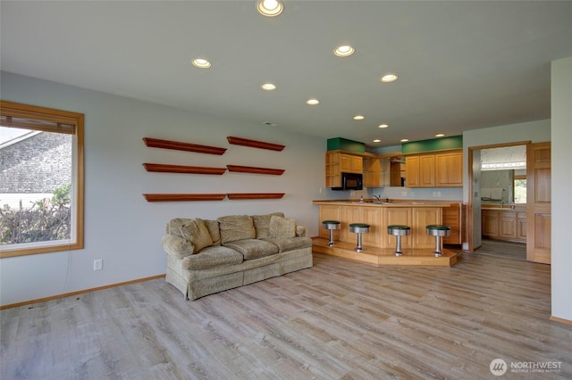 unfurnished living room with light wood-type flooring, a sink, baseboards, and recessed lighting