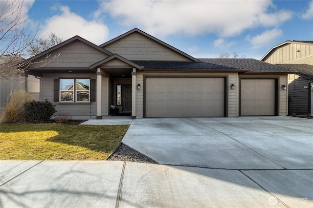 view of front of property featuring a garage, a front yard, driveway, and a shingled roof