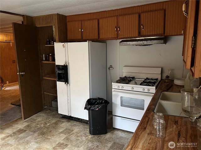 kitchen featuring wooden walls, white appliances, brown cabinets, and under cabinet range hood