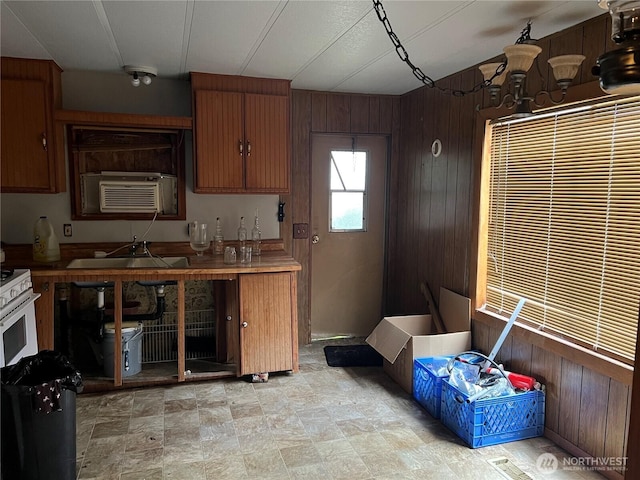 kitchen featuring a sink, wooden walls, and white range with gas cooktop