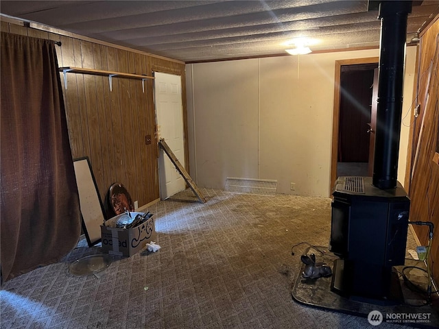 basement featuring carpet floors, a wood stove, and wood walls