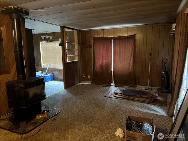 interior space with a wood stove, wood walls, and light carpet