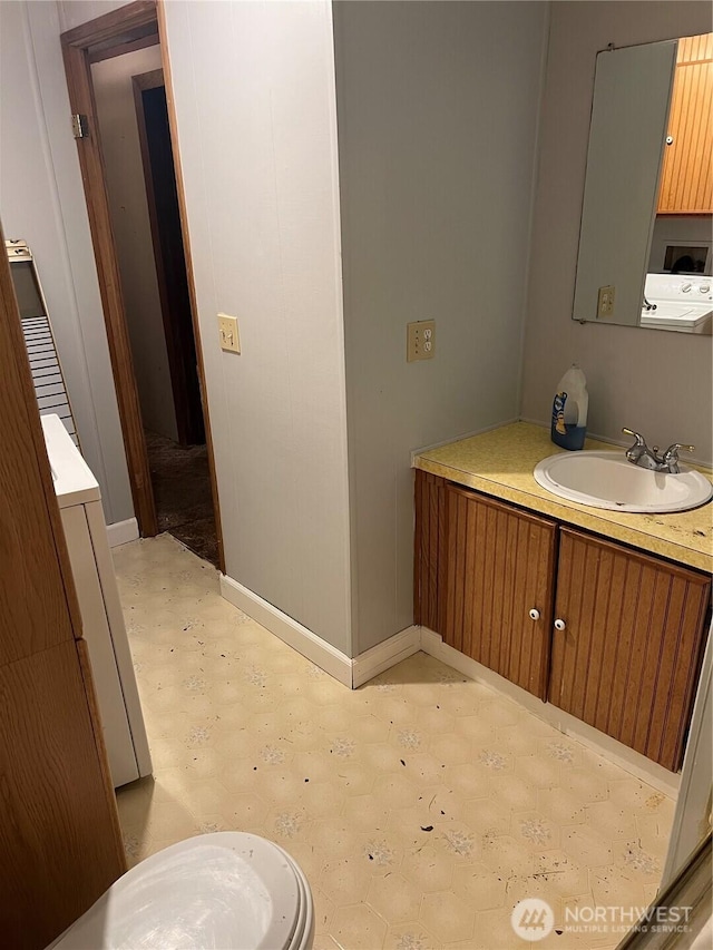 bathroom with washer / clothes dryer, vanity, and baseboards