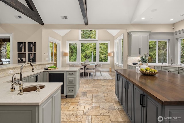 kitchen featuring butcher block countertops, gray cabinets, visible vents, and stone tile floors