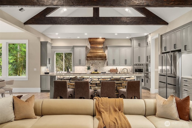 kitchen featuring custom range hood, stainless steel appliances, open floor plan, and gray cabinetry