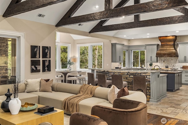 interior space featuring stone tile floors, tasteful backsplash, visible vents, custom range hood, and gray cabinets