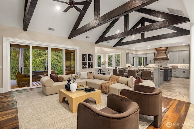 living area featuring high vaulted ceiling, a wealth of natural light, and visible vents