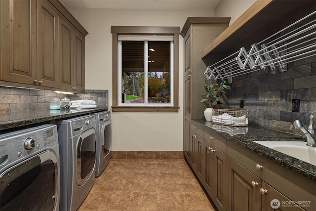 washroom featuring washer and dryer, cabinet space, a sink, and baseboards