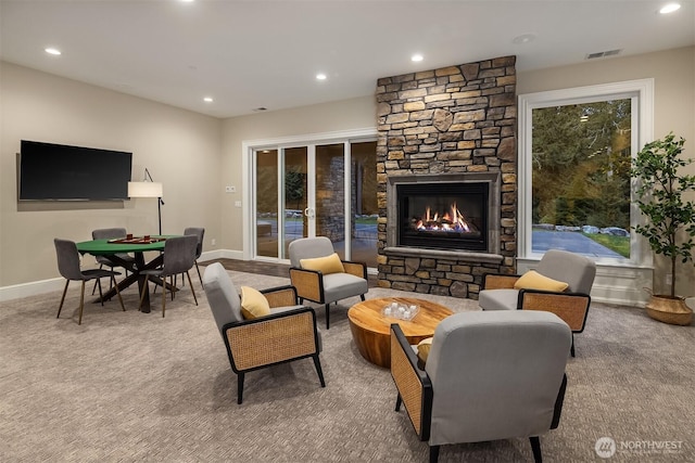 carpeted living room with baseboards, a stone fireplace, visible vents, and recessed lighting