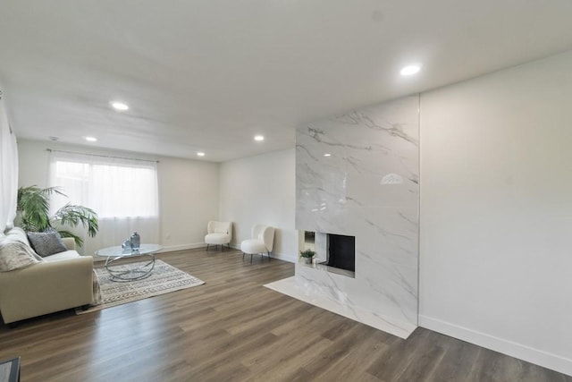 living area featuring recessed lighting, dark wood-style flooring, baseboards, and a premium fireplace