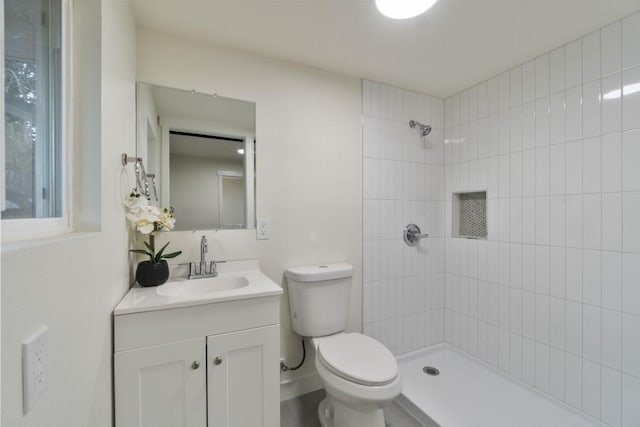 full bathroom with toilet, a tile shower, and vanity