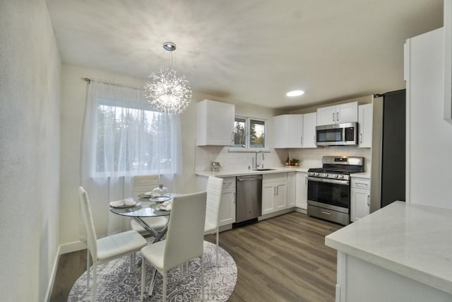 kitchen with light countertops, hanging light fixtures, appliances with stainless steel finishes, white cabinetry, and a sink