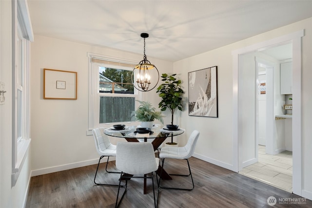 dining space with baseboards, an inviting chandelier, and wood finished floors