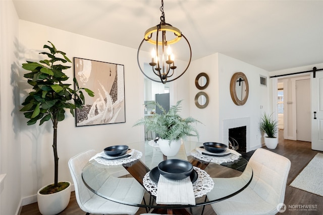 dining room with a barn door, a notable chandelier, visible vents, baseboards, and dark wood finished floors