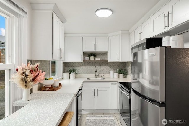 kitchen featuring a sink, stainless steel appliances, light countertops, and white cabinets