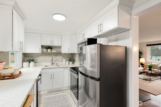 kitchen featuring a sink, white cabinetry, light countertops, appliances with stainless steel finishes, and decorative backsplash