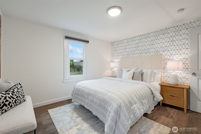 bedroom with an accent wall, dark wood finished floors, and baseboards