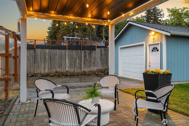 view of patio / terrace featuring an outbuilding, a detached garage, and fence