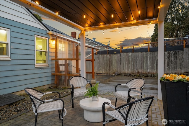 patio terrace at dusk featuring fence