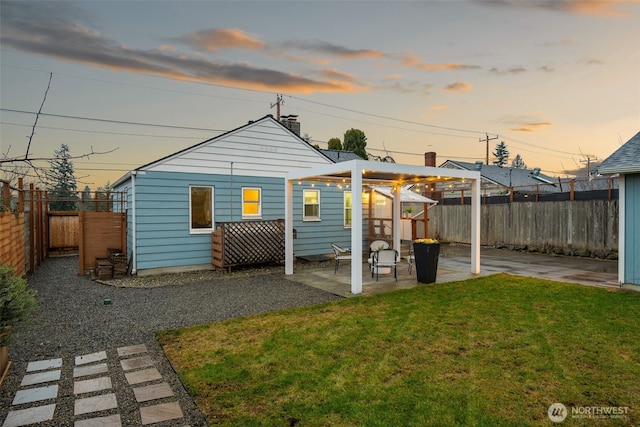 rear view of house with a patio, a lawn, and a fenced backyard