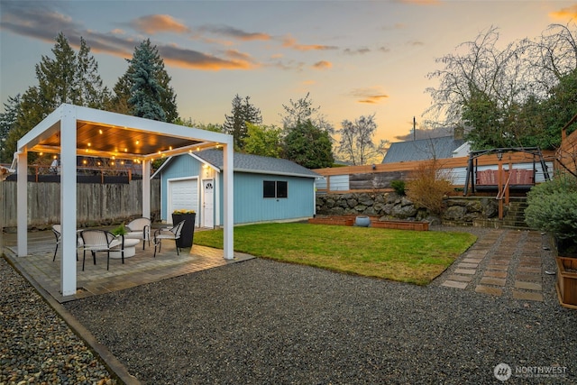 view of yard featuring a garage, an outbuilding, a patio area, and fence