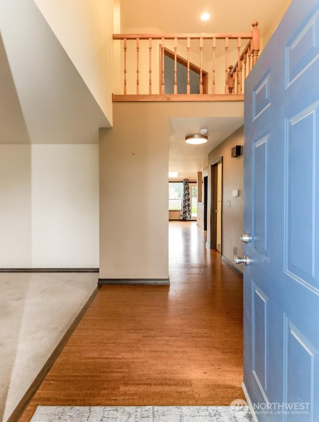 foyer featuring a high ceiling, wood finished floors, and baseboards