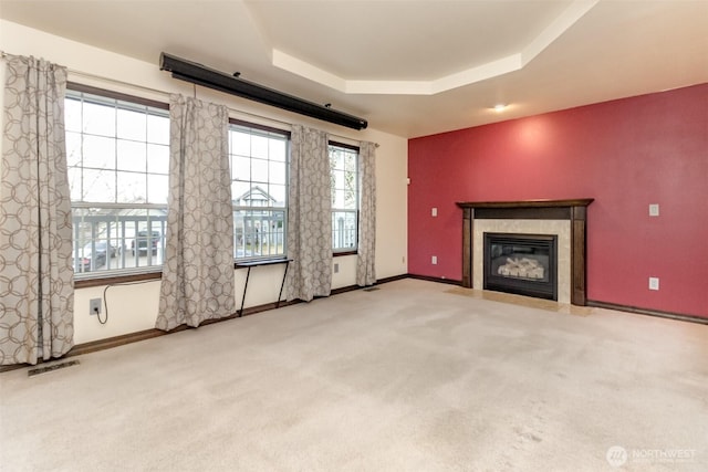 unfurnished living room with carpet, visible vents, a raised ceiling, and a wealth of natural light