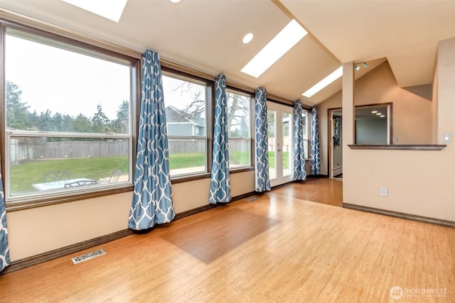 interior space featuring lofted ceiling with skylight, baseboards, visible vents, and wood finished floors