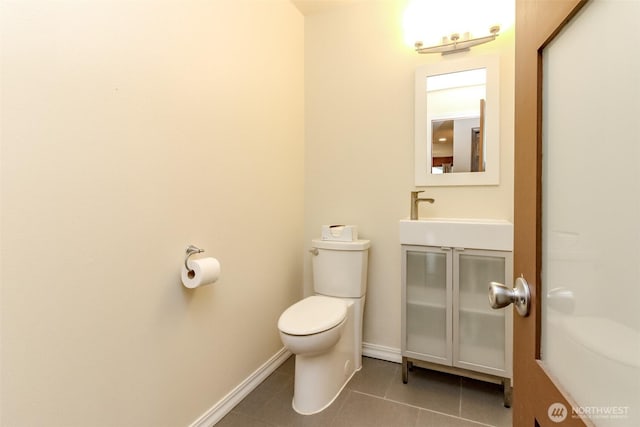 bathroom featuring toilet, tile patterned flooring, baseboards, and a sink