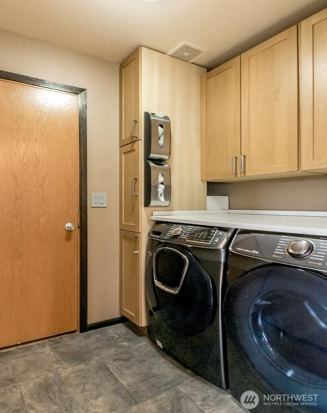 washroom featuring visible vents, cabinet space, and washer and dryer