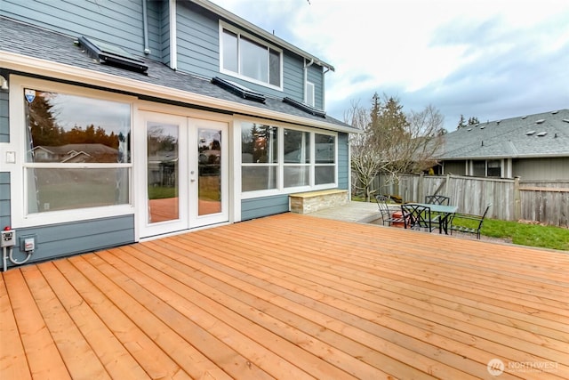 deck with outdoor dining space, french doors, and fence