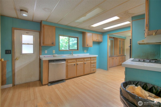 kitchen featuring dishwasher, light countertops, light wood-type flooring, gas stovetop, and a sink