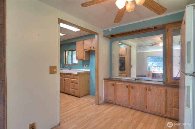 kitchen featuring brown cabinetry, light wood-type flooring, freestanding refrigerator, and ceiling fan